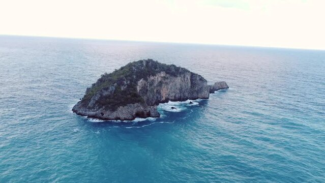 This footage aws made with a drone, at the end of the day, at sunset, with a uninhabited island as the main object, and the beach with trees at the background