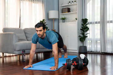 Athletic and sporty man doing pushup on fitness mat during home body workout exercise session for...