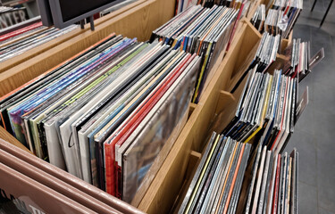 Large collection of vinyl records displayed in wooden bins, diverse popular music album selection...