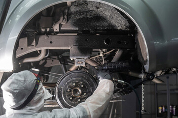 The master sprays an anti-corrosion compound on the bottom of the car.