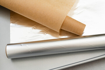 Close-up photograph showcasing essential baking tools including parchment paper, aluminum foil, and a baking pan