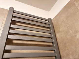 Simple contemporary wall-mounted heater in a bathroom placed near a wall, space heater, ladder towel radiator rail in a modern residential apartment, hotel, object closeup detail, nobody, no people
