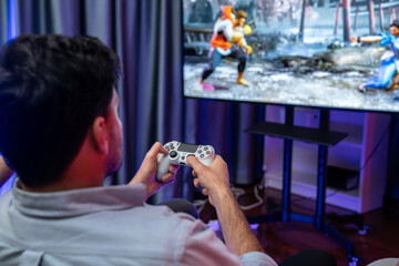 Focusing photo of holding joystick with fighting gaming competition of video game on blurred...