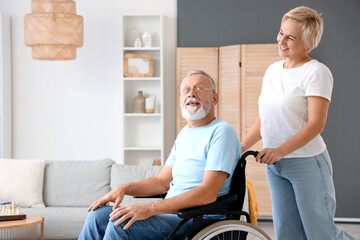 Mature woman with her husband in wheelchair at home
