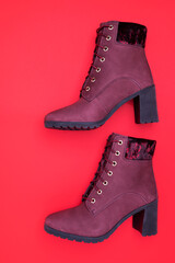 pair of red of suede women's half-boots with high heels on a red background. Stylish demi-season women's shoes.