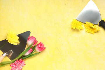 Composition with building trowels and flowers on color background. International Women's Day