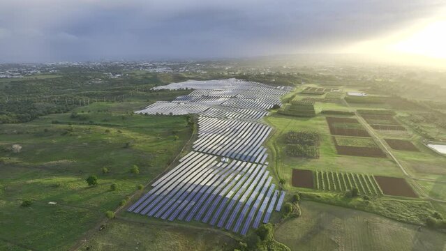 Large solar panel array beautiful green landscape on Caribbean island with dramatic sunlit sky - Aerial 4K HDR drone footage 