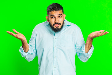 What. Why. Angry Indian man raising hands in indignant expression, asking reason of failure, demonstrating disbelief irritation by troubles. Arabian young guy isolated on green chroma key background