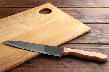 One sharp knife and board on wooden table, closeup