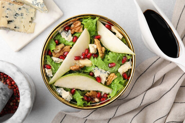 Delicious pear salad in bowl and sauce on light table, flat lay