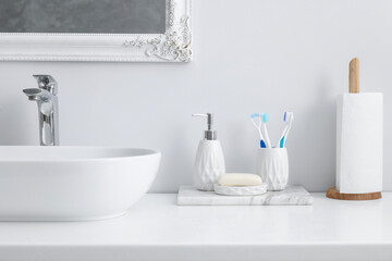 Different bath accessories and personal care products near sink on bathroom vanity