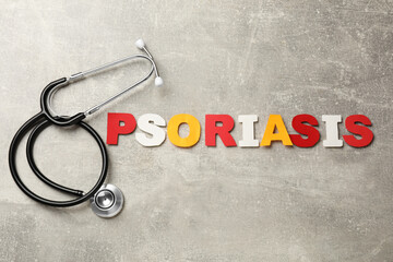 Word Psoriasis made of paper letters and stethoscope on light gray textured table, flat lay