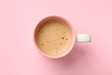 Aromatic coffee in cup on pink background, top view