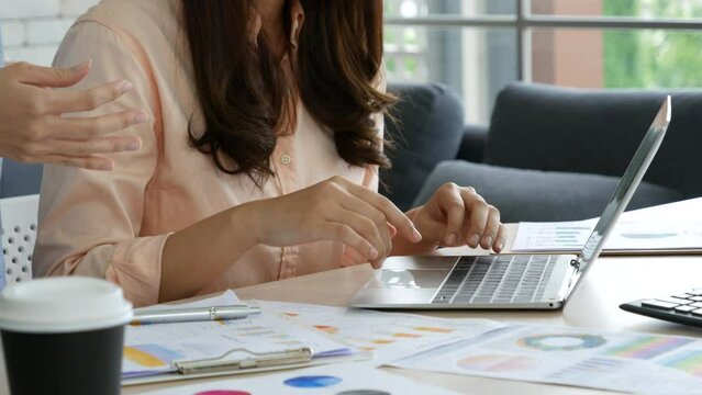 Two asian Female freelance reading financial graph charts Planning analyzing marketing data. Asian people team working office firm. Two businesswomen team meeting using laptop at company office desk.