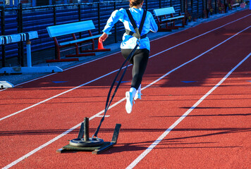 Girl running pulling a sled with weight on a track