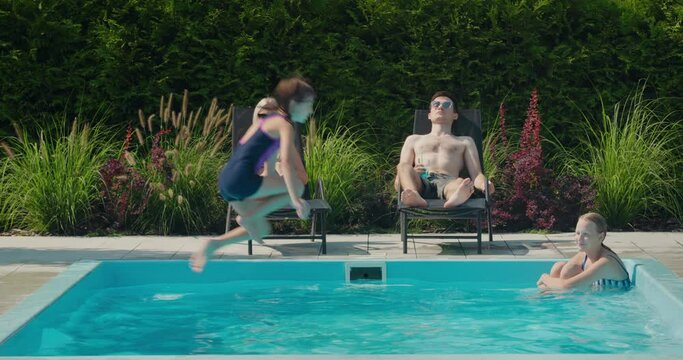 The family relaxes by their pool in the backyard of the house. Adults sunbathe on sun loungers, two children swim in the pool