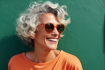 Close up portrait of a smiling middle-aged woman in orange sunglasses.