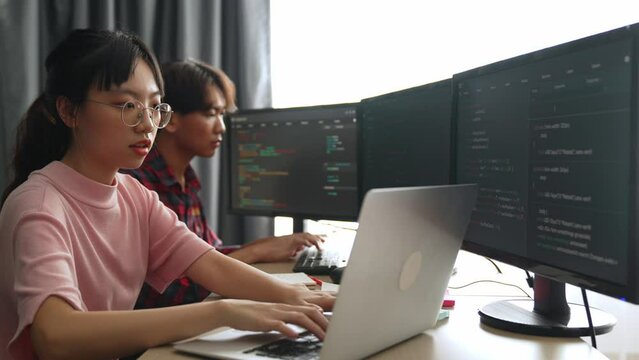 Slow motion back end software developer engineer for computer programming working together on debugging writing computing code, solving complex algorithms display on monitor in office. Burgeoning