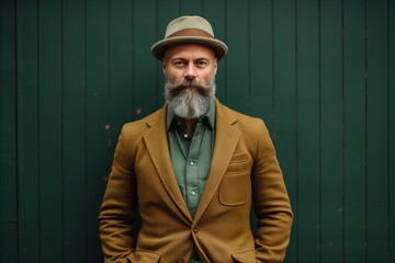 Portrait of a bearded man in a hat and a coat on a green background
