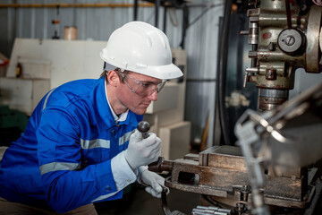 Industry engineer wearing safety uniform control operating lathe grinding machine working in...