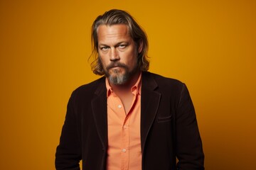 Handsome mature man with long gray hair and beard. Studio shot on yellow background.