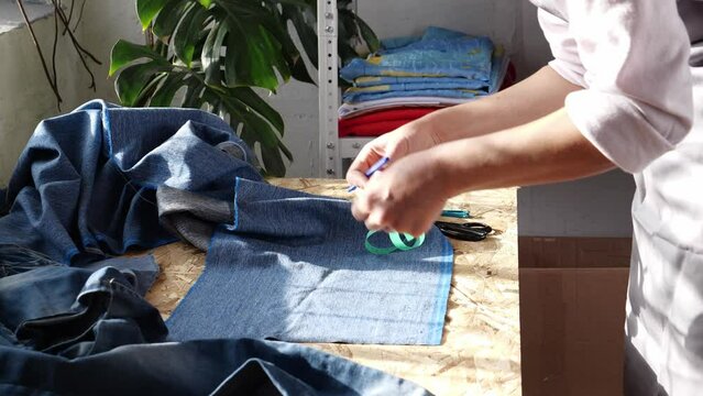 Upcycling and DIY. A woman sews a new thing out of old jeans. New life into wardrobe