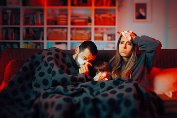 Family Suffering from a Cold Sitting on the Couch Together. Mother, father and child being contagious with the grippe 
