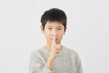 内緒のポーズをする男の子　白背景