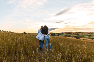 back view of two female friends hugging in a field