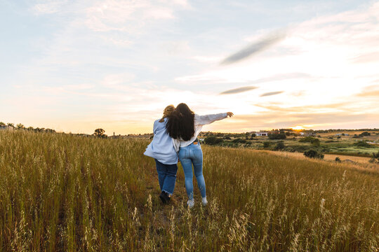 back view of two female friends hugging in a field