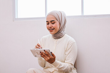 Young successful muslim woman with braces using tablet while sitting at work