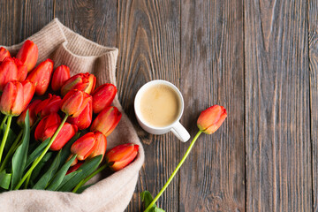 Fresh orange tulips and cappuccino mug with spring composition. Greeting card with copy space for Valentine's Day, Woman's Day and Mother's Day.