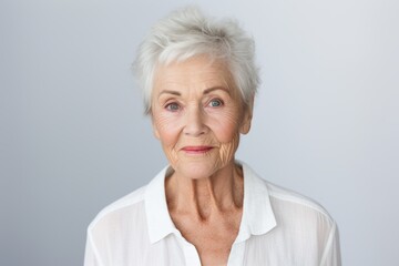 Portrait of a senior woman looking at the camera against grey background - obrazy, fototapety, plakaty