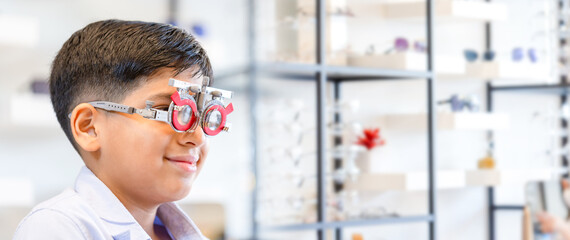 Indian-thai boy choosing glasses in optics store, Boy doing eye test checking examination in...