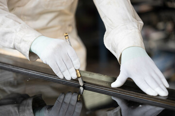 Male glass technician works on installing glass using installation tools and checking the condition of the work piece.