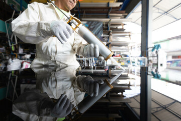 Male glass technician works on installing glass using installation tools and checking the condition of the work piece.