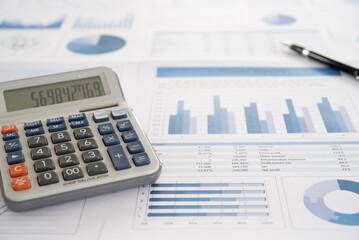 calcualtor with business report and financial statement on desk of data analyst.