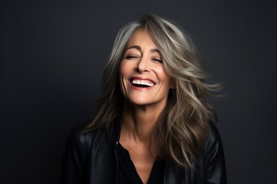 Portrait of a beautiful middle aged woman laughing against a dark background