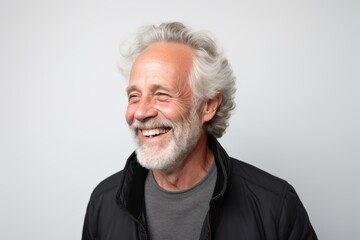 Portrait of a happy senior man smiling at the camera on grey background