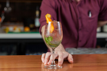 Bartender making a fruity summer cocktail at a bar. 