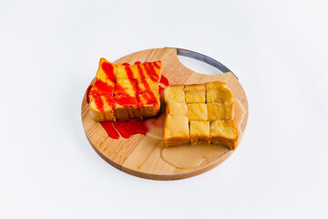 Top view of traditional french toasts with strawberries jam and condensed milk on wooden plate with white background. Bread toast baked in butter, topped with strawberry jam and condensed milk.