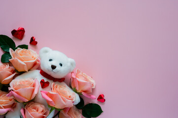White teddy bear doll with pink roses and love shape on pink background for Valentines day concept.