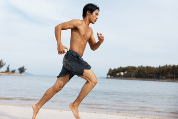 Fototapeta na wymiar Active Asian Athlete Enjoying a Sunset Beach Run: Strong, Muscular Man Embracing the Power and Freedom of Outdoor Fitness