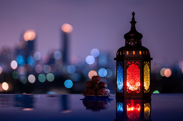 Lantern and small plate of dates fruit with night sky and city bokeh light background for the Muslim feast of the holy month of Ramadan Kareem.
