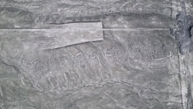 Top down aerial view over the Nazca humanoid creature lines in Peruvian desert.