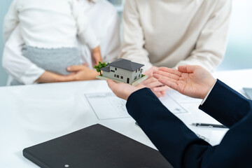 住宅の模型を見て話す親子と営業をする女性
