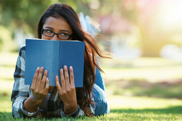Woman, student and lying with book on green grass for literature, studying or story in nature....