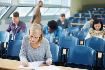 Writing, university and woman student in classroom studying for test, exam or assignment....