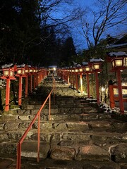 The road to the snow-covered torill (shrine gate) and red lantern box at Kifune Shrine at Kyoto, Japan at winter night 