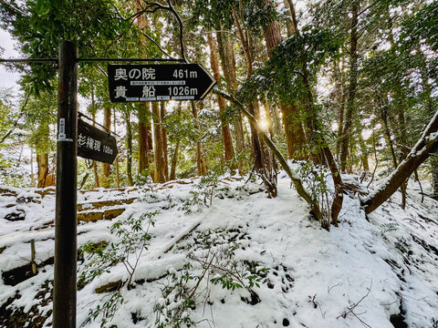 The sign on the hiking trail in the snowy forest to the Kuramadera Temple at Kyoto, Japan on a winter day 